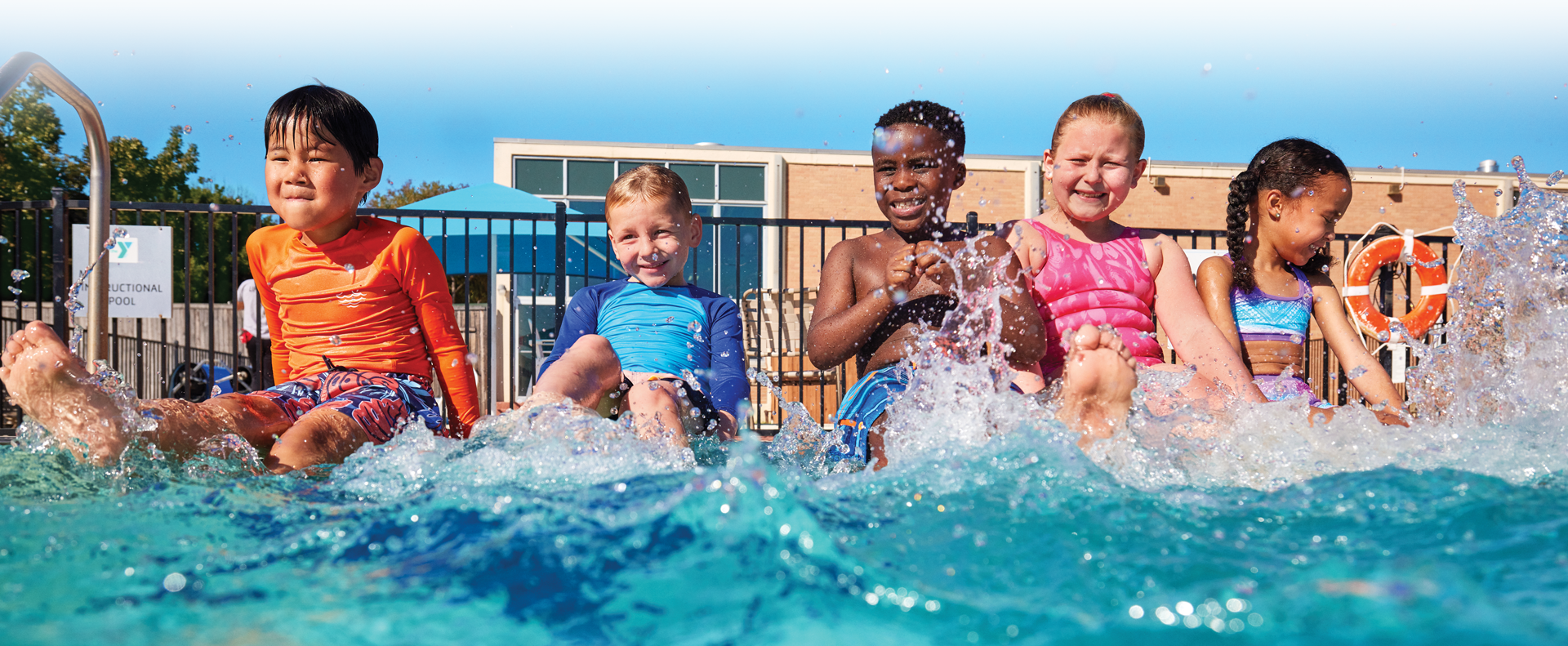 kids splashing and kicking while sitting on the side of the pool